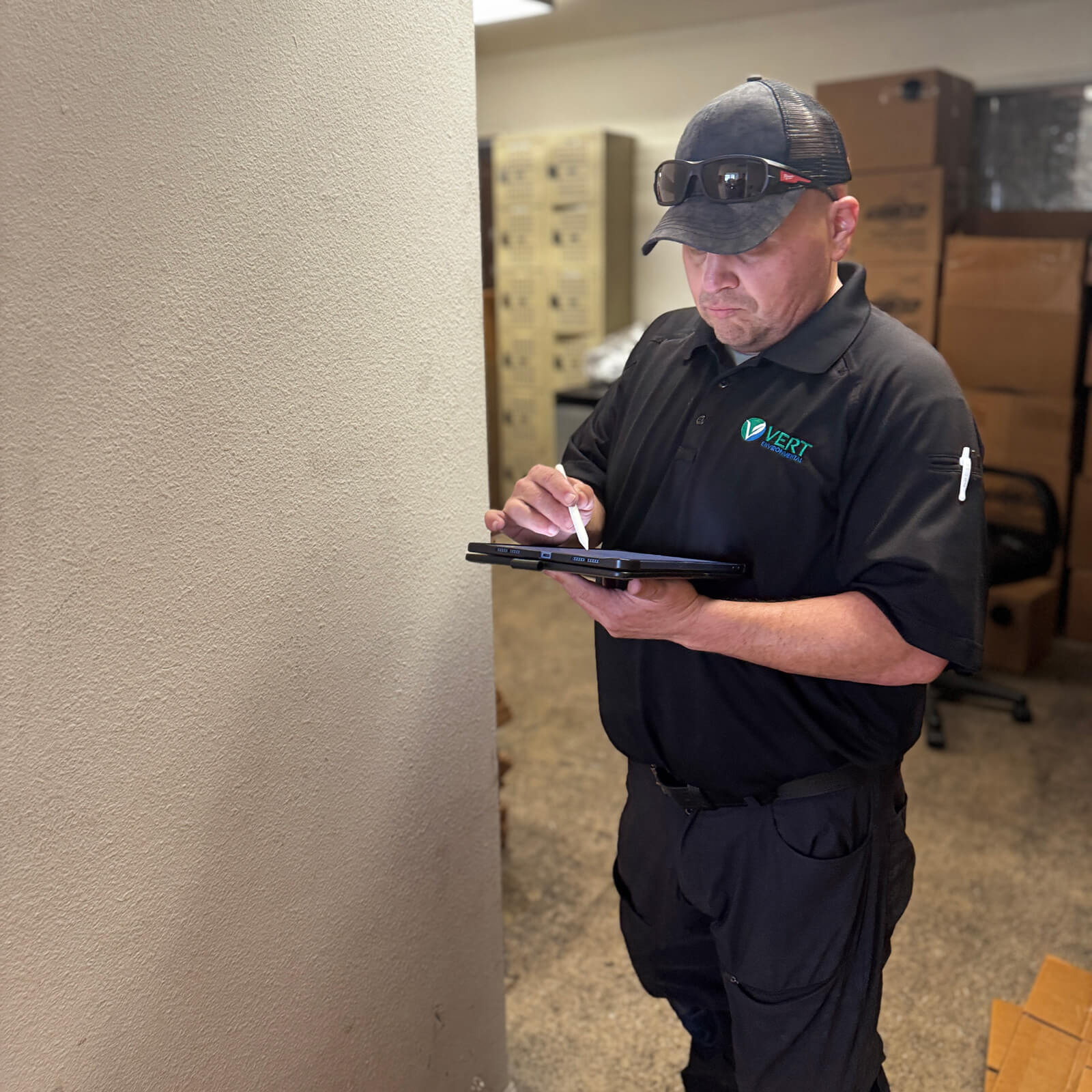 Professional specialist logging site survey data on a tablet during a comprehensive environmental hazard inspection.