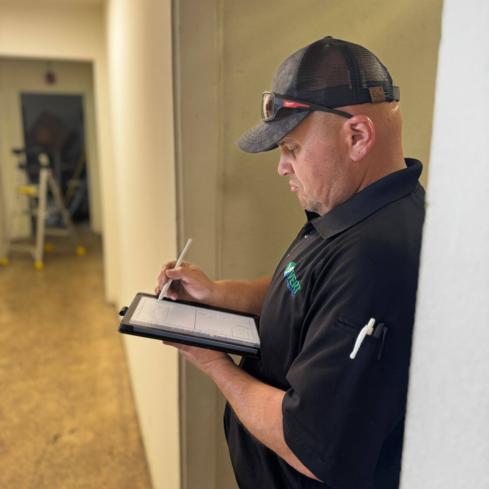 Technician recording site survey data on a tablet during an environmental hazard assessment for Clear Tech Pools.